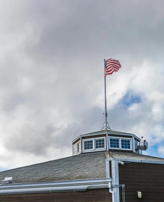 an american flag is on top of a building with a roof