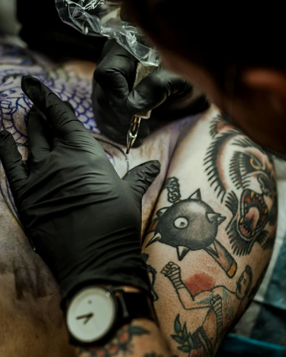 arm tattoo being done by an individual with an owl tattoo