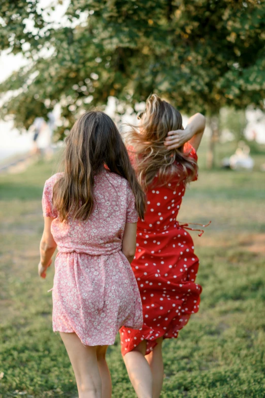 two women in short dresses walking in a field