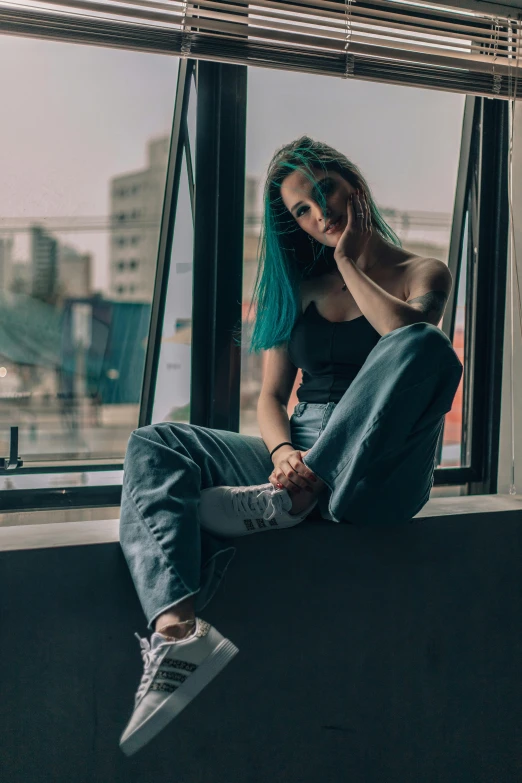 woman with blue hair sitting on the windowsill looking out