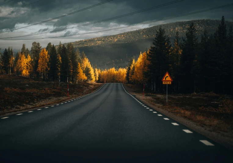 a dark and stormy road with mountains in the background