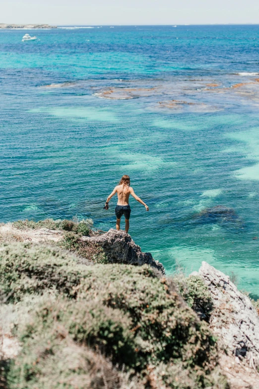 a man standing on a cliff overlooking a body of water