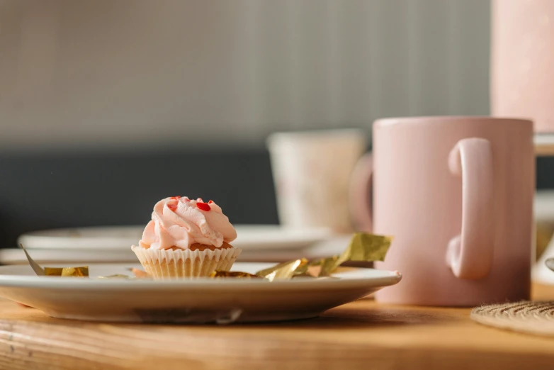 a cupcake on a plate with two gold pieces