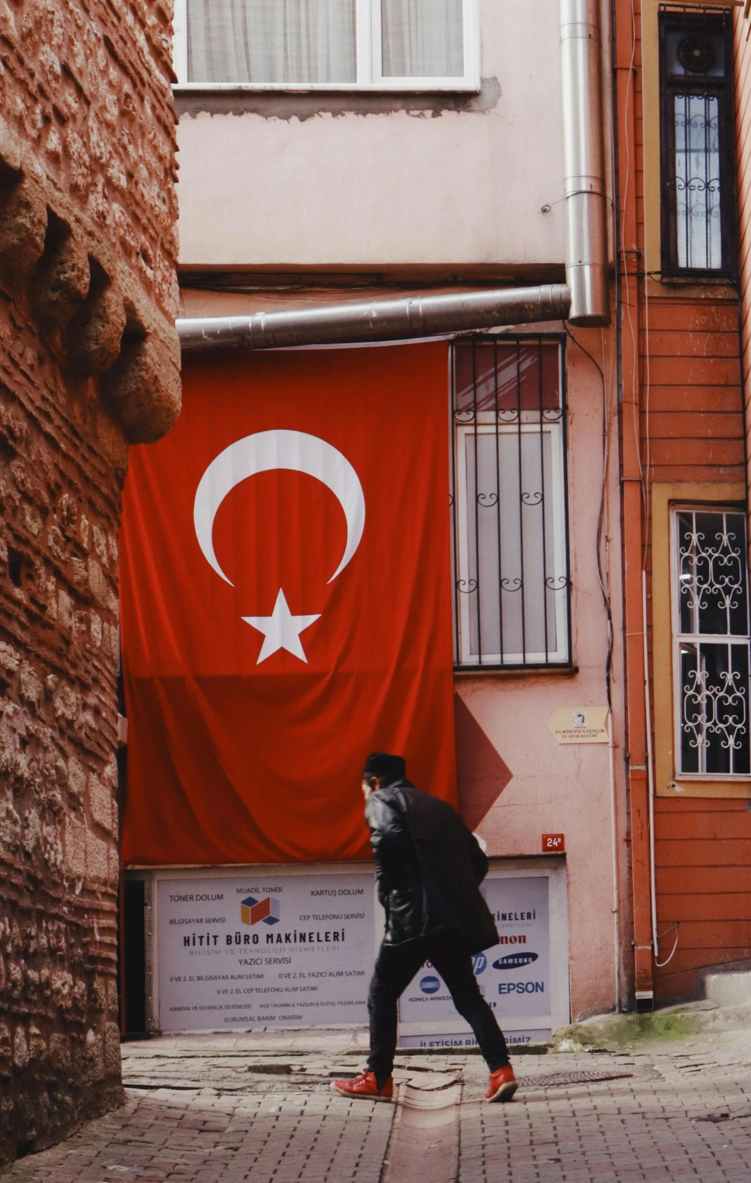 a person is walking past a building that has a turkish flag on it