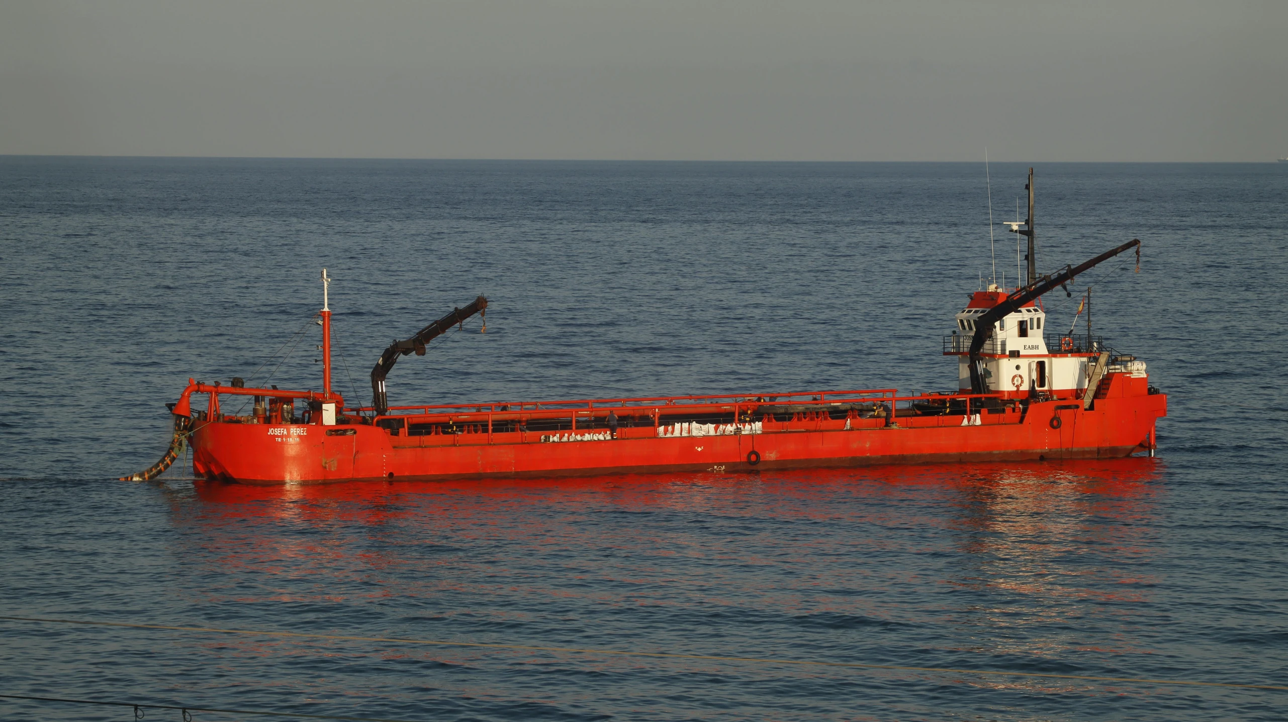 an orange ship is in the ocean on a cloudy day