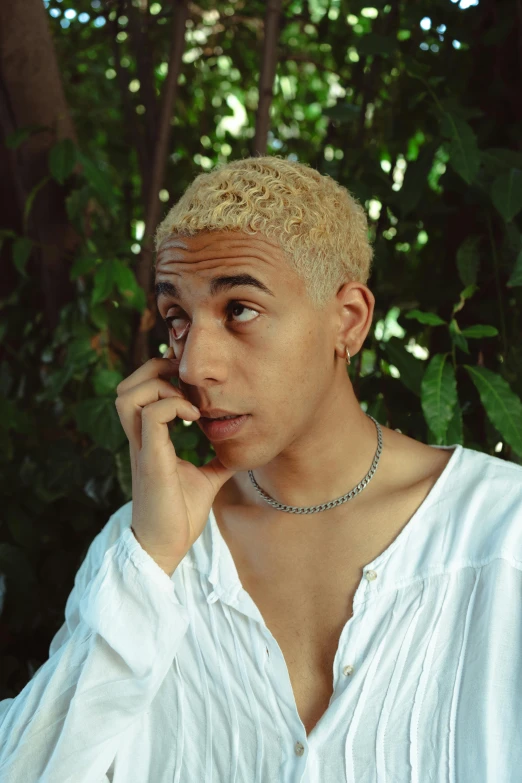 a person sitting in front of some trees talking on a cellphone