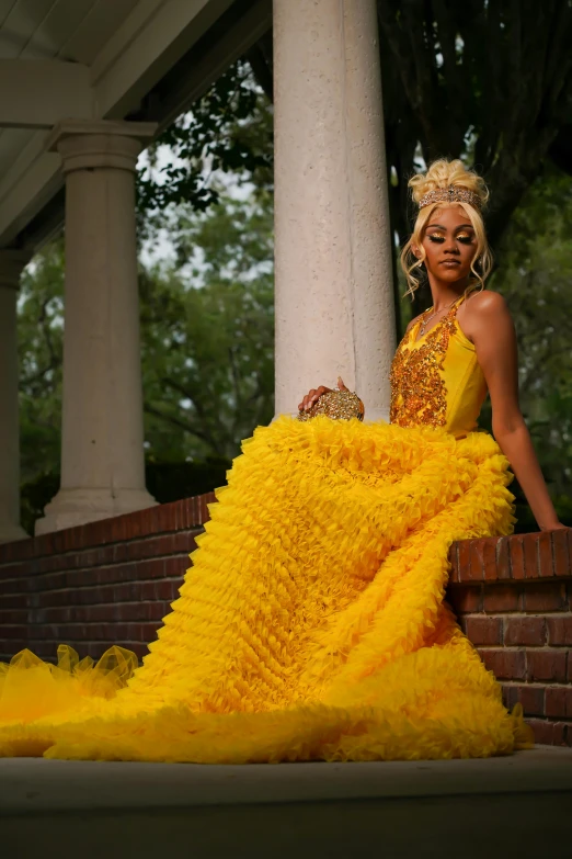 a woman in a yellow dress stands on a red brick step