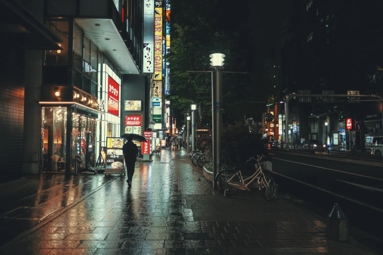 someone with an umbrella walks down the street at night