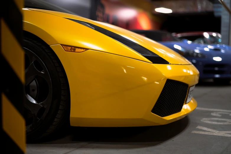 a yellow sports car sits parked in front of several other blue cars