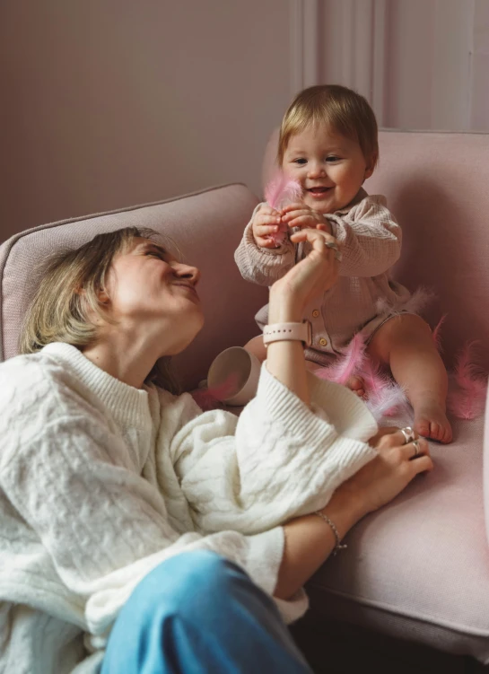 a woman and her baby on a pink couch