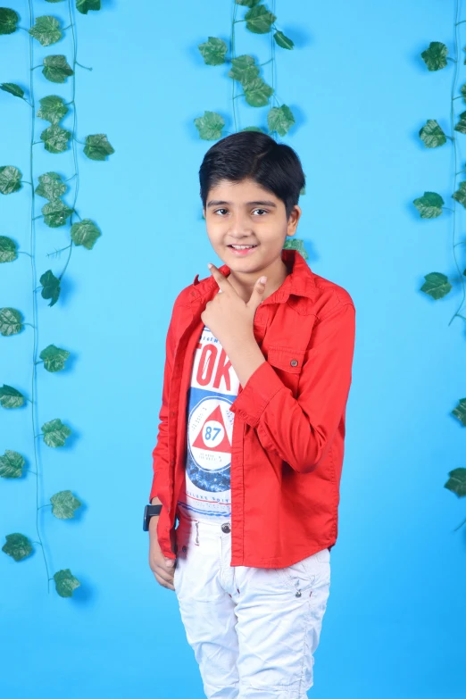 a young indian boy wearing white pants and a red shirt