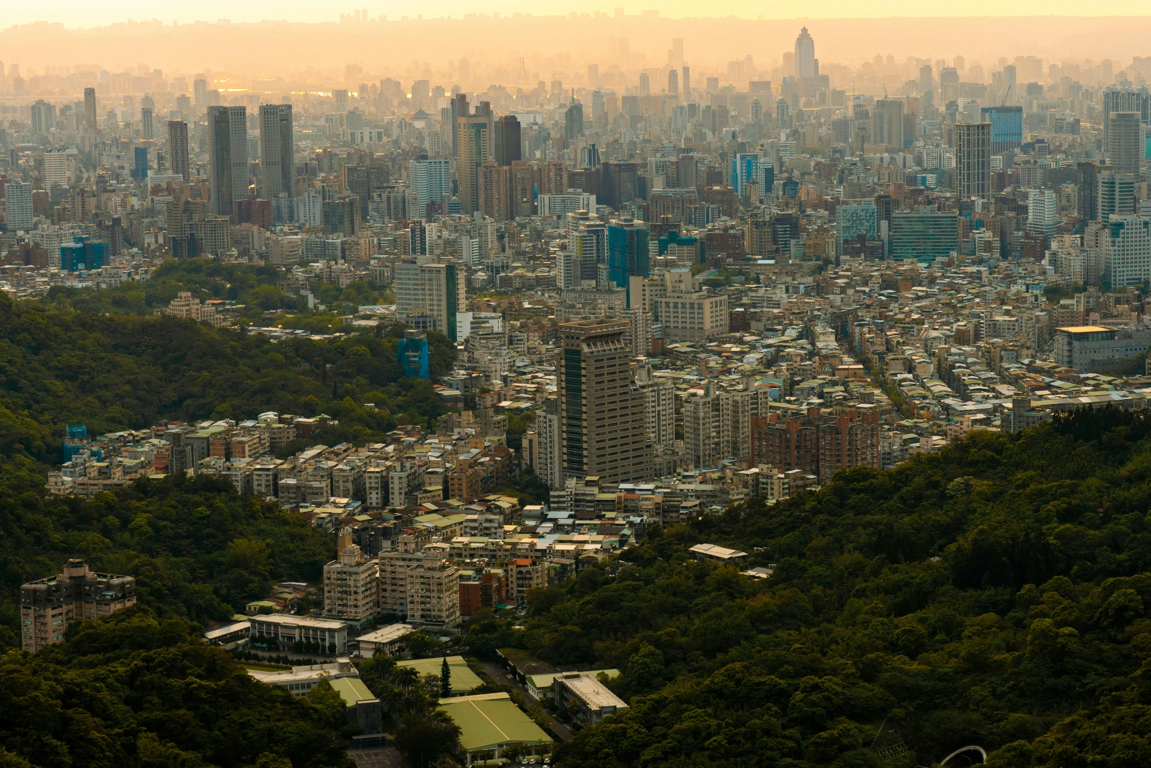 an aerial view of a city with green trees and hills