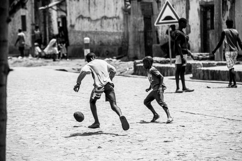 there are two boys playing soccer outside on the street