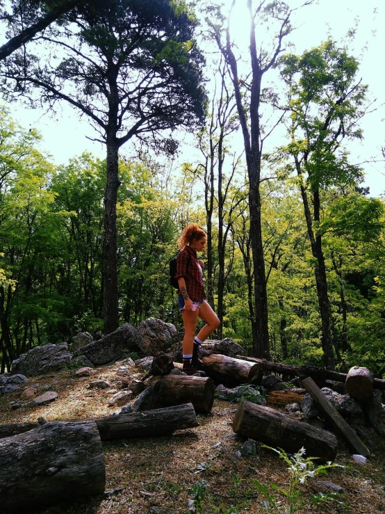 a woman stands on a log and walks across the grass