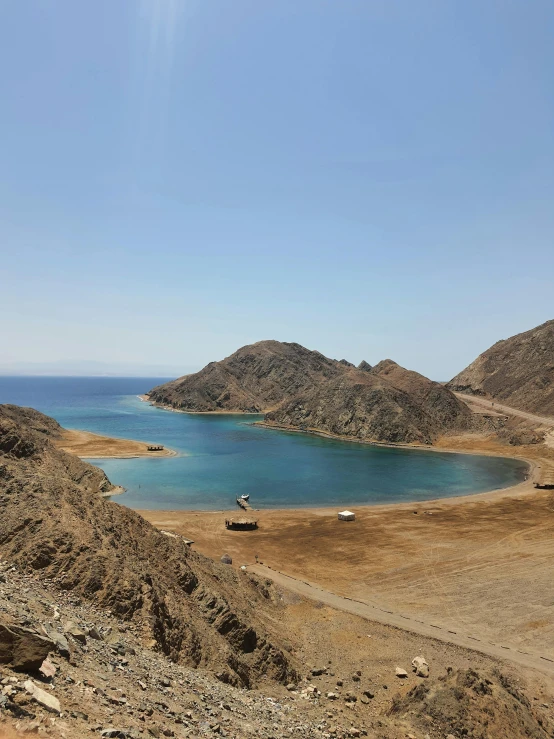 blue waters surrounded by sand and rocky hills