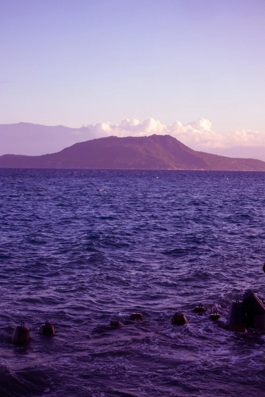 two people looking out over the ocean at a large rock