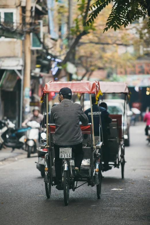 a man riding a cart that is pulling a motorcycle down the street