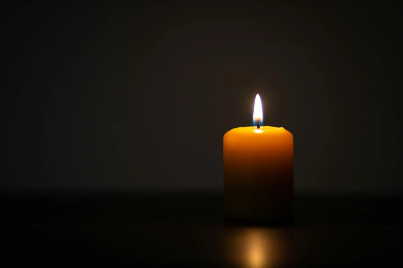 a burning candle with a dark background