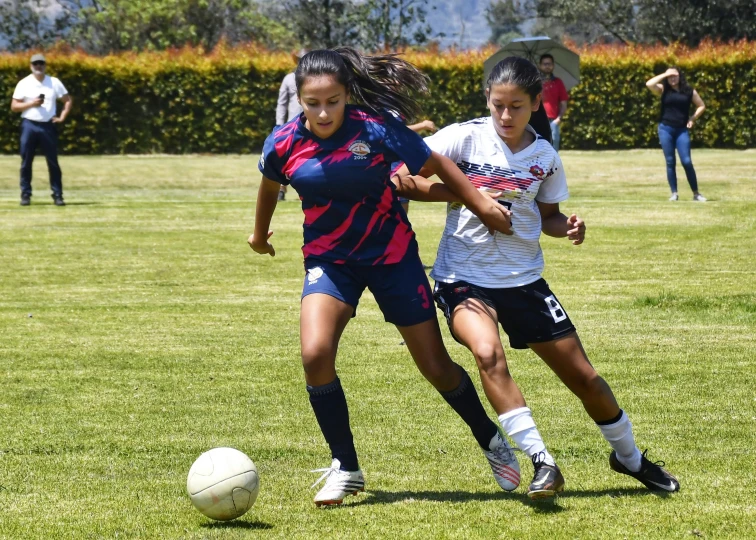 girls on a soccer field playing soccer against each other