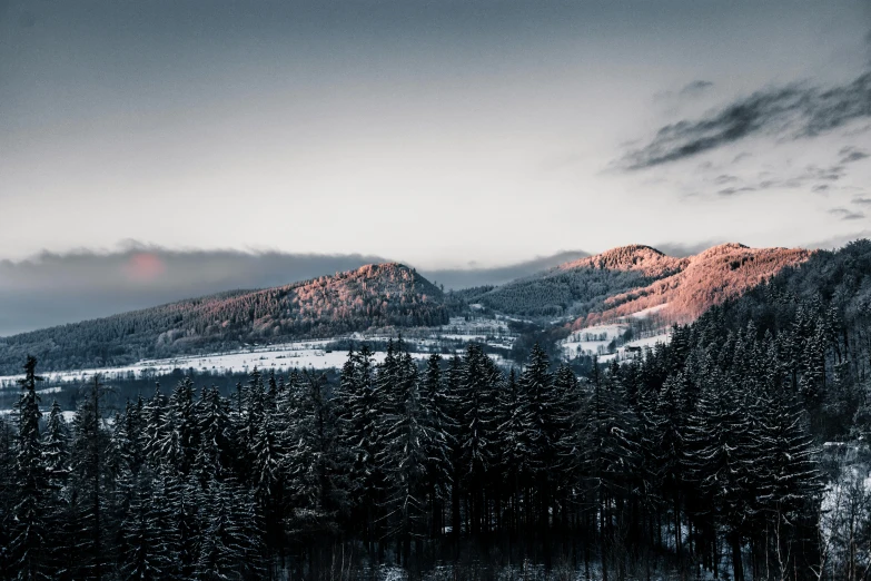 snow - capped mountain with trees, sky and sun rays