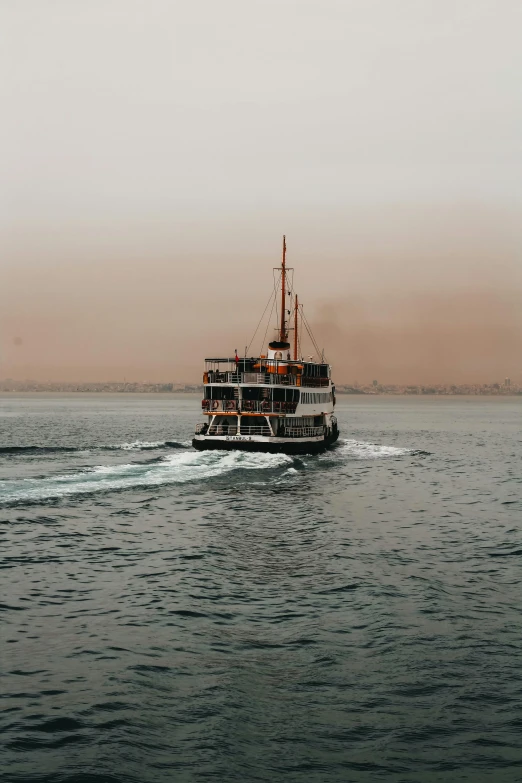 a ferry boat moving through the water on a very hazy day