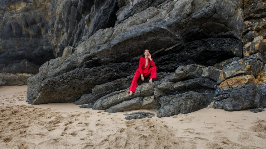 a woman is leaning against some rocks on the beach