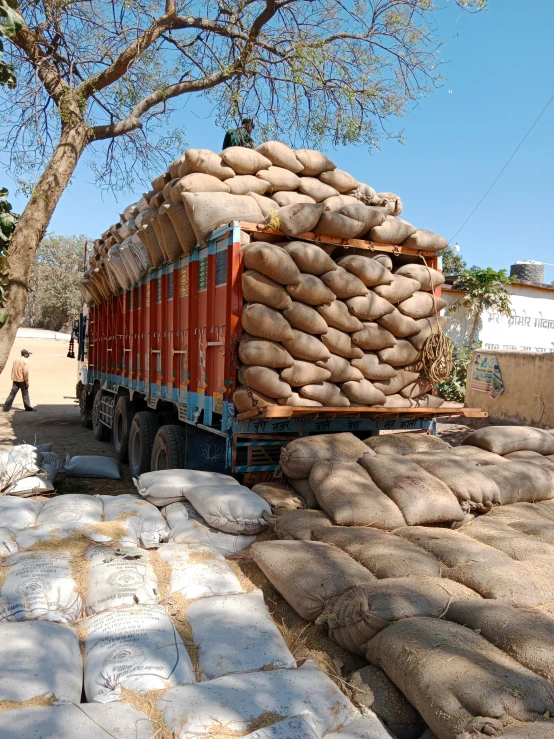 a big truck loaded with sand bags parked by some trees