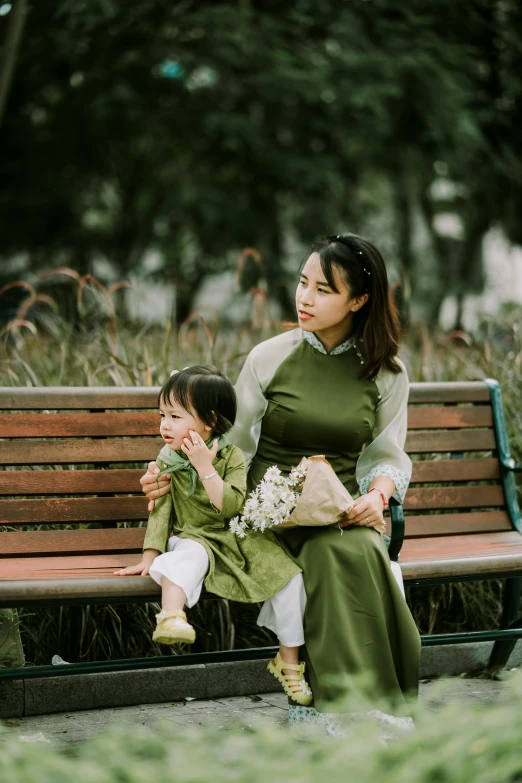 a woman and little boy sitting on a park bench