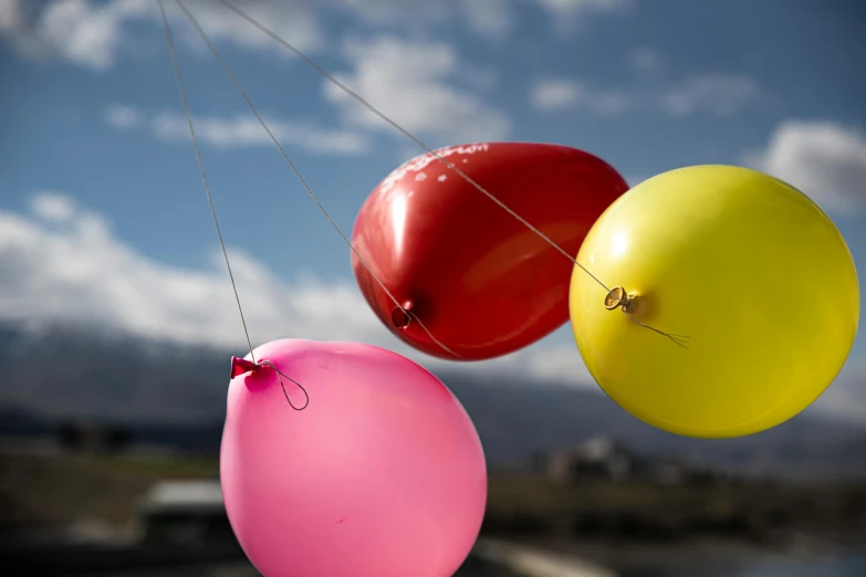 two balloons are suspended in the air and one is pink and the other is yellow