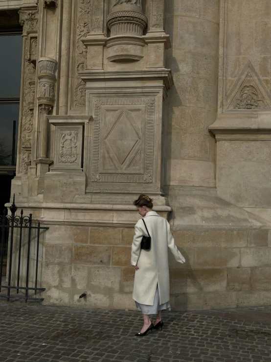 a person in a white coat is near an old building