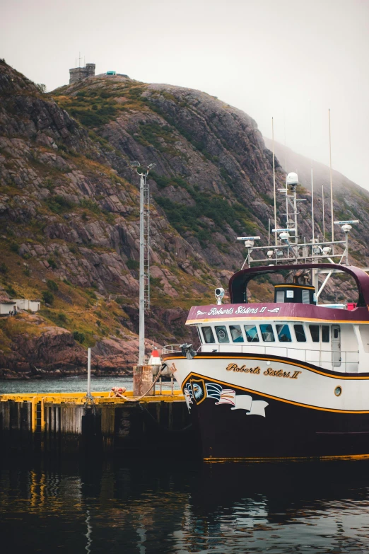 a boat sits docked at a dock by mountains