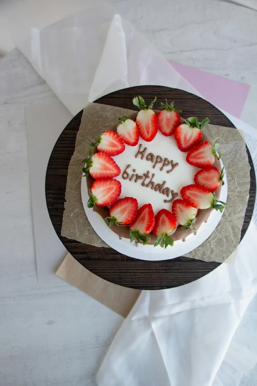 a white birthday cake covered with strawberries