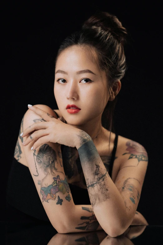 young asian woman with tattoos sitting at a table