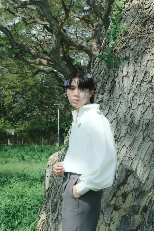 a girl in white shirt standing by tree