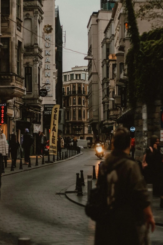 a group of people walking across a street next to tall buildings