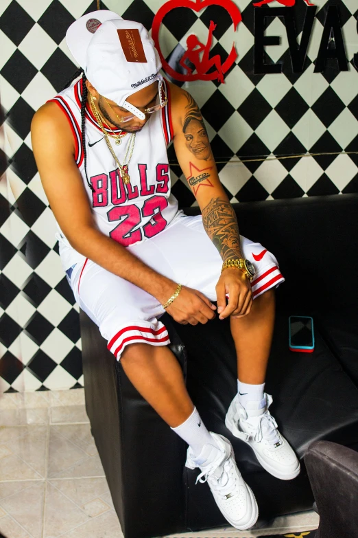 a young man sits on a stool while wearing a basketball uniform