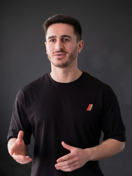 a man talking in front of a grey backdrop