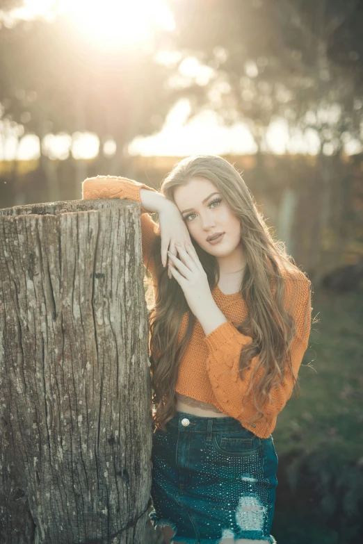 a woman is leaning against the wooden post