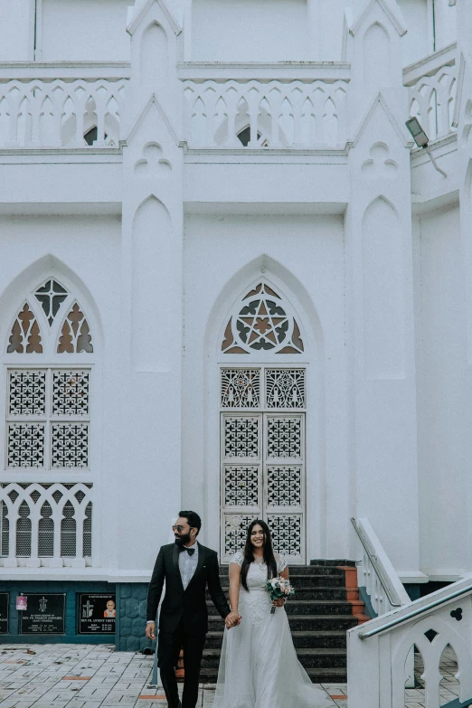 a bride and groom are walking towards the stairs outside the white church