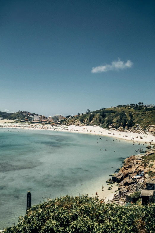 a sandy beach with blue water next to the ocean