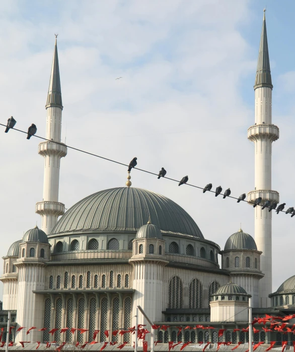 the large building has many towers and a bunch of birds