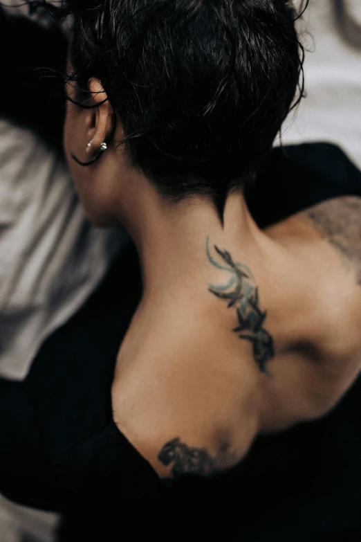 back of girl with tattoos on left chest, shoulder and right arm