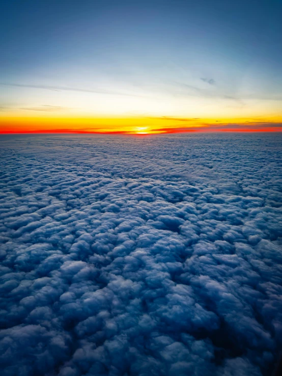 the sun is setting over a cloud covered plain