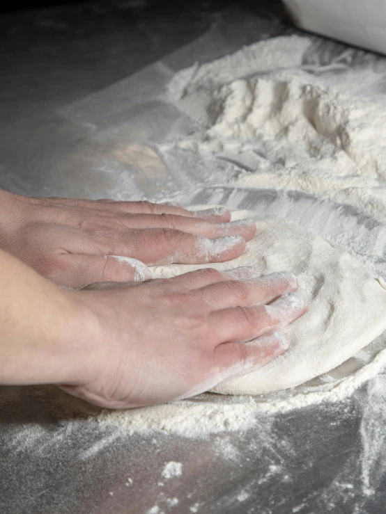 hand resting on floured dough in hand over flour