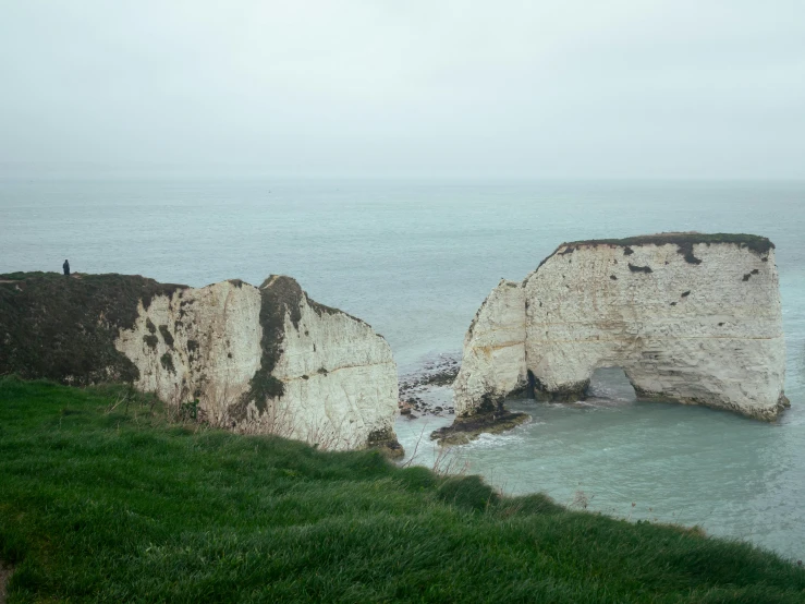 three people standing on the edge of an ocean cliff