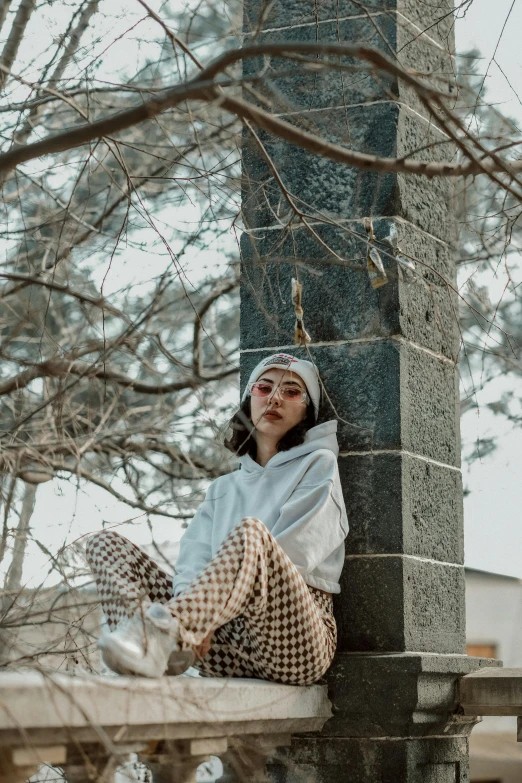 the girl is sitting on the porch near a tree