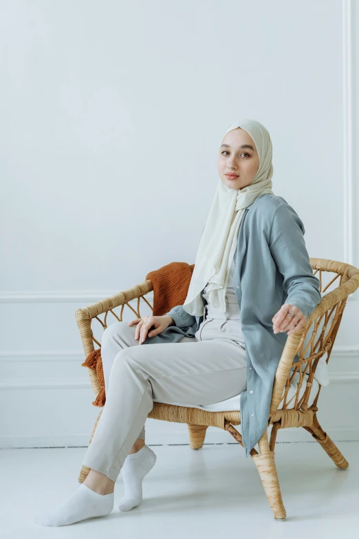 a woman sits on a chair in front of a white wall