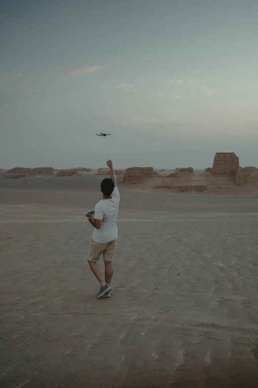 a man in white shirt flying a kite in desert area