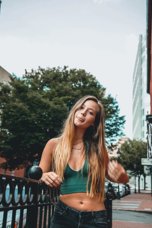 a woman in a green shirt poses on the street