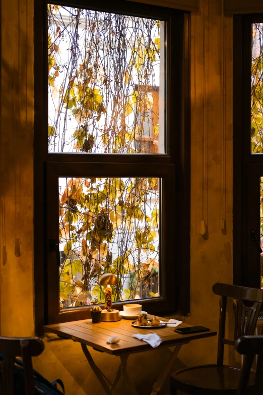 a wooden table with two chairs next to two windows